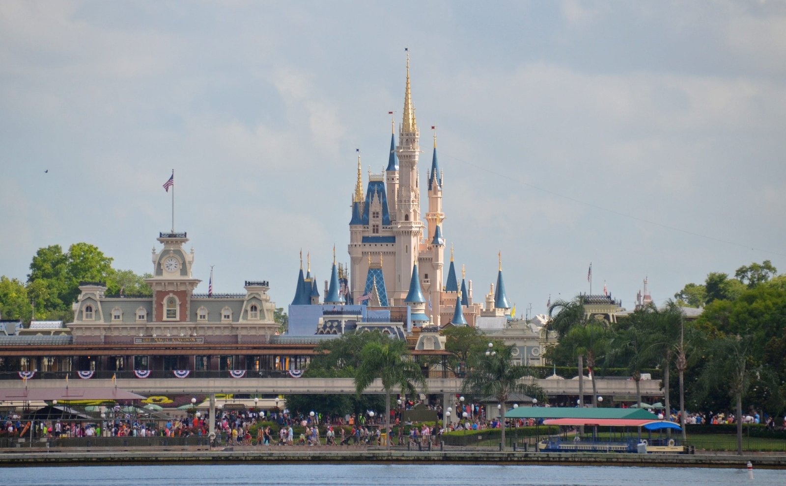 a castle with many people walking by a lake